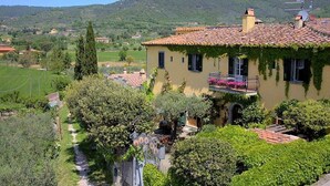 Une maison avec un toit en tuiles, un balcon orné de fleurs et un jardin.