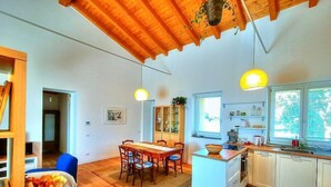 A modern kitchen with wooden cabinets, a dining area with a table and chairs, and pendant lighting.