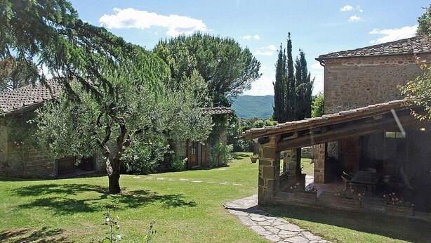A stone building with a covered patio and a tree in the foreground. - Villa Al Borgo: A welcoming two-story villa located in a characteristic village, with Free WI-FI. (Radda in Chianti)