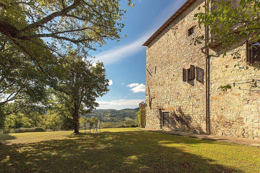 A stone building with a grassy courtyard and a large tree.