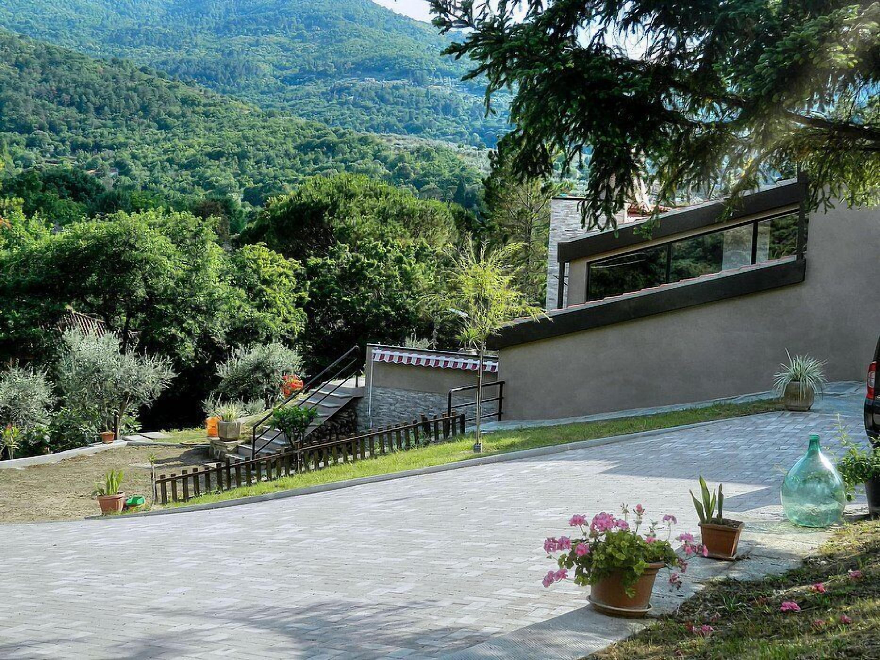 Edifici modern amb façana de pedra, una petita escala i plantes en testos.