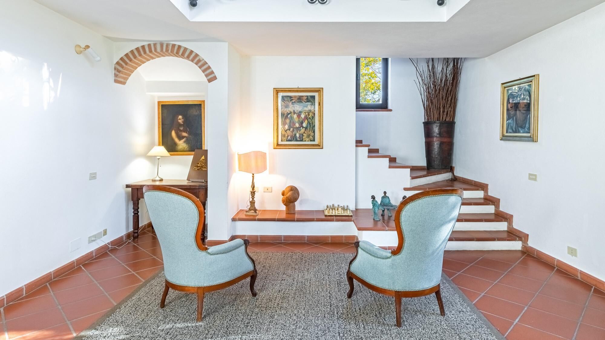 A spacious living area with two light blue armchairs, a coffee table, a fireplace, and a staircase leading to another level.