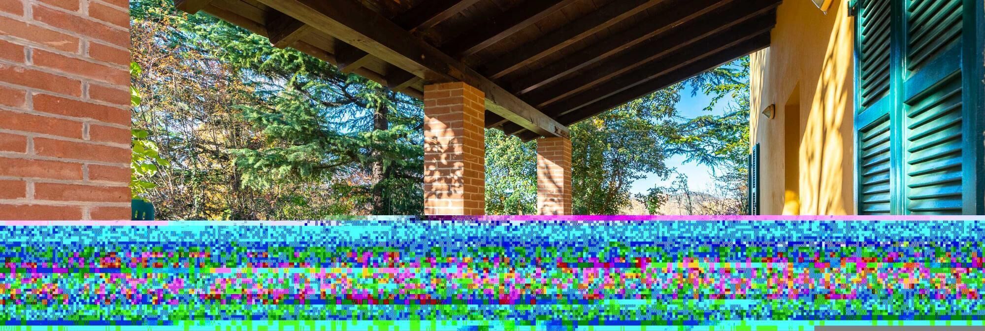 A covered outdoor area with brick pillars and a wooden ceiling.