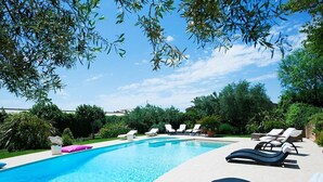 Une piscine avec des chaises longues et une terrasse carrelée.