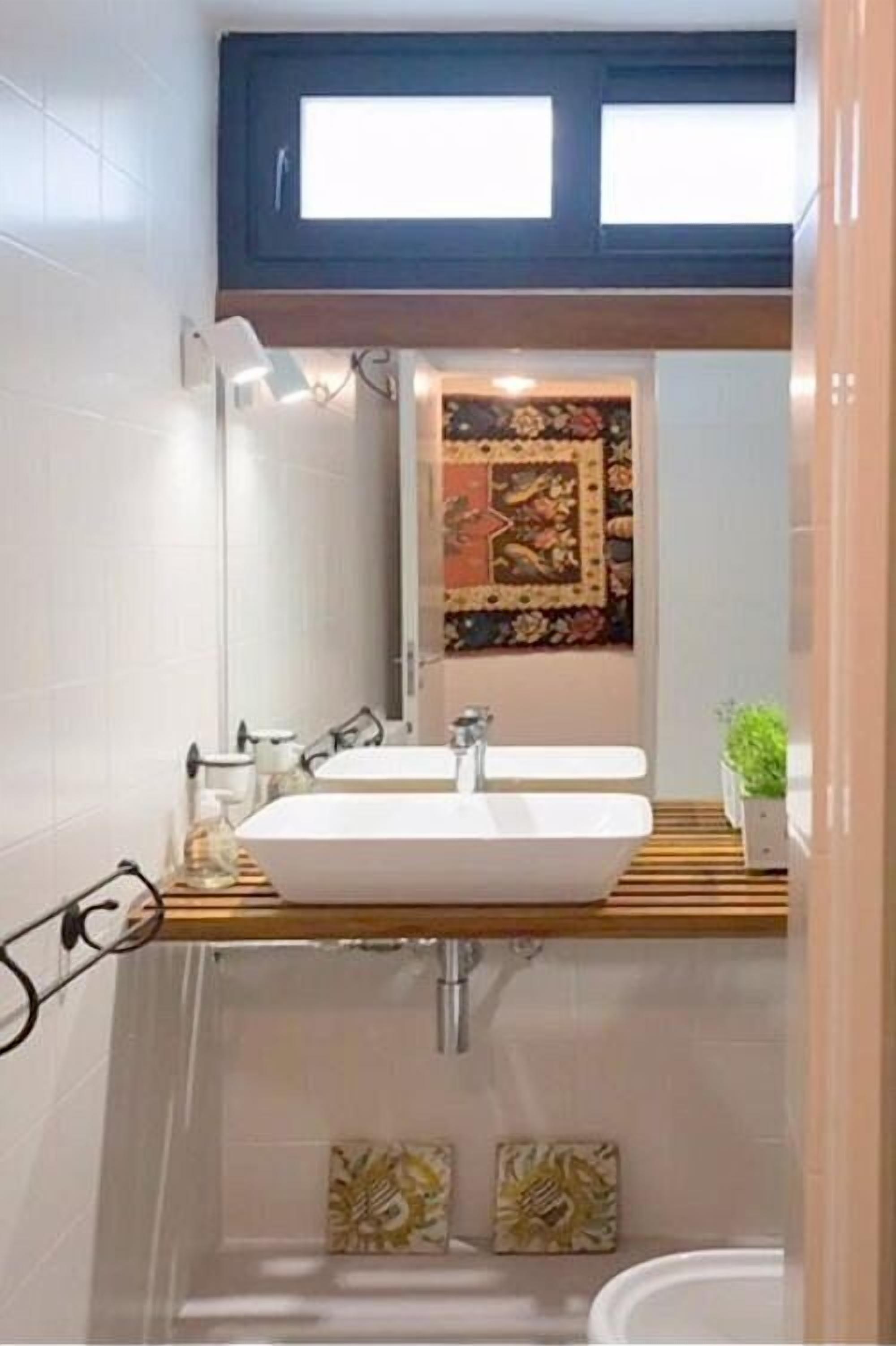 Ein modernes Badezimmer mit einem großen Spiegel, einem Holzbadezimmerunterschrank und einer dekorativen Fliesenfassade.
