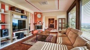Een woonkamer met een televisie, speakers, een open haard en een groot raam.