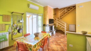 A dining area with a table and chairs, a kitchen with a stove, and a staircase leading to an upper level. - Casa Nilla: A cheerful two-story townhouse situated in a quiet location, a few minutes from the town center, with Free WI-FI. (Agropoli)