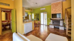 A spacious living area with a kitchen, dining table, and a fireplace. - Casa Nilla: A cheerful two-story townhouse situated in a quiet location, a few minutes from the town center, with Free WI-FI. (Agropoli)