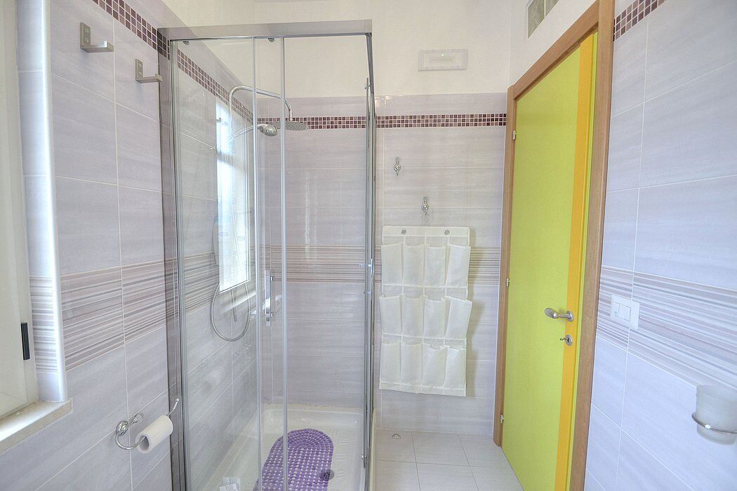 A bathroom with a glass-enclosed shower, a toilet, and a sink.