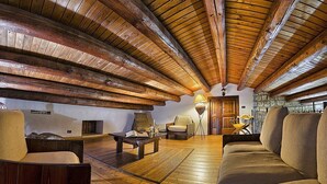 Une pièce spacieuse de style loft, avec un haut plafond en bois, un canapé confortable, une petite table et une chaise.