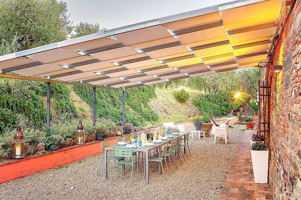 Eine Terrasse im Freien mit überdachter Sitzgruppe, einer Ziegelwand und einem Garten.