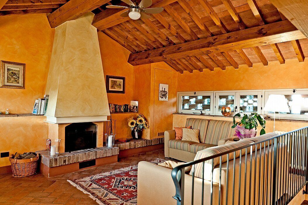 A cozy living room with a fireplace, a sofa, a coffee table, and a ceiling fan.