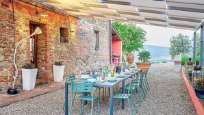 An outdoor dining area with a stone wall, a covered patio, and a view of the landscape. - Villa Collarina Grande: An elegant and welcoming two-story age-old farm house surrounded by the greenery, with Free WI-FI. (Montelupo fiorentino)
