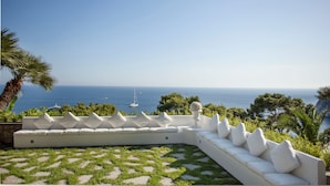 Un área de estar exterior blanca con vista al mar.