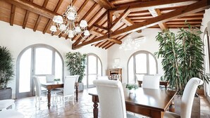 A spacious dining area with a wooden ceiling, white chairs, and a large dining table. - Villa Stellaria: An elegant and welcoming three-story villa located on top of a small hill, with Free WI-FI. (Reggello)