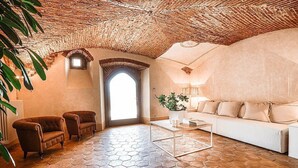 A spacious living room with a hexagonal tile floor, a white sofa, two armchairs, a coffee table, and a large window with natural light. - Villa Stellaria: An elegant and welcoming three-story villa located on top of a small hill, with Free WI-FI. (Reggello)