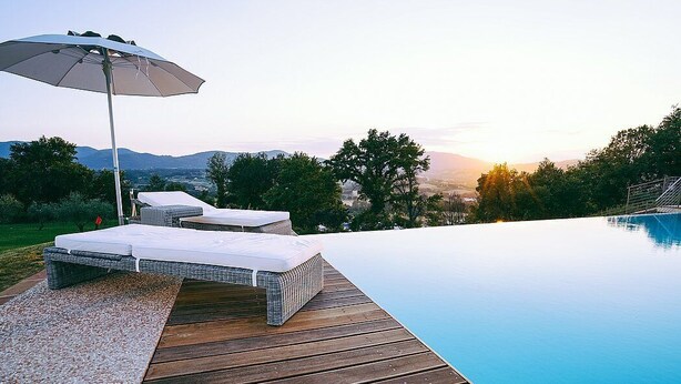 A wooden deck with a pool, a lounge chair, and an umbrella. - Villa Stellaria: An elegant and welcoming three-story villa located on top of a small hill, with Free WI-FI. (Reggello)