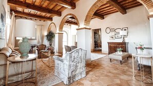 A spacious living room with high ceilings, exposed wooden beams, and a tiled floor. There are several seating areas with sofas and a coffee table. - Villa Stellaria: An elegant and welcoming three-story villa located on top of a small hill, with Free WI-FI. (Reggello)