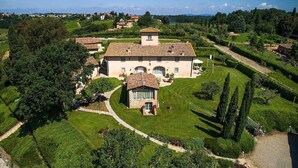 A large, rectangular building with a tiled roof, surrounded by well-maintained lawns and trees.
