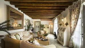 A cozy living room with wicker furniture, a wooden ceiling, and a view of the adjacent dining area.