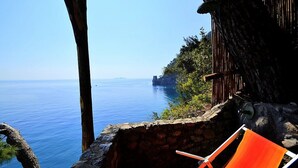 Eine Steinsäule mit Holzlatten blickt auf das klare, blaue Meer.