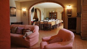 Una sala de estar acogedora con un sofá y un sillón, un comedor con una mesa y sillas, y una chimenea de ladrillo.