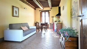 Un salón acogedor con sofá, una mesa de comedor con sillas, una zona de cocina y una puerta de madera.