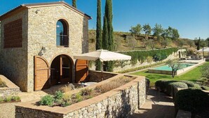 A stone building with arched doorways, a pool, and a well-maintained garden.