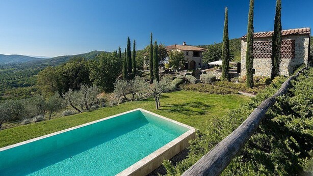 A pool with a clear blue water, surrounded by a grassy area and trees.