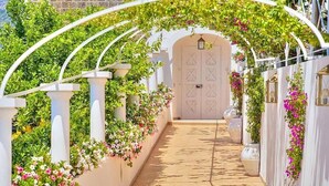 A pathway leading to a white door, flanked by white columns and lush greenery. - Villa Atena: A charming two-story villa which faces the sun and the sea, with Free WI-FI. (Praiano)
