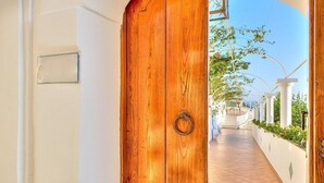 A wooden door leading to a covered outdoor area with white columns and a tiled pathway. - Villa Atena: A charming two-story villa which faces the sun and the sea, with Free WI-FI. (Praiano)