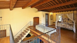A spacious room with a wooden staircase, a bed with a canopy, and a rustic wooden ceiling. - Villa Campanella: A characteristic and welcoming two-story age-old farm house surrounded by the greenery, with Free WI-FI. (Perugia)