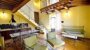 A spacious living area with a staircase, a dining table, and a sofa. - Villa Campanella: A characteristic and welcoming two-story age-old farm house surrounded by the greenery, with Free WI-FI. (Perugia)