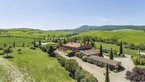 A large, red-roofed villa with a paved driveway and a small garden, surrounded by rolling green hills and sparse trees. - Villa Pernice: An elegant and welcoming two-story villa surrounded by the greenery, with Free WI-FI. (Castiglione D'orcia)