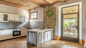 A kitchen with a stone wall, a window, and a door leading to an outdoor area. - Villa Pernice: An elegant and welcoming two-story villa surrounded by the greenery, with Free WI-FI. (Castiglione D'orcia)