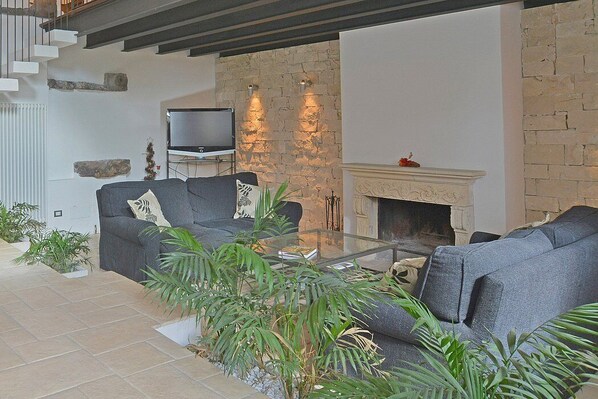 Una sala de estar moderna con chimenea de piedra, televisor de pantalla plana y asientos cómodos.