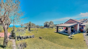 Une maison avec un patio, une pelouse et une vue sur la mer.