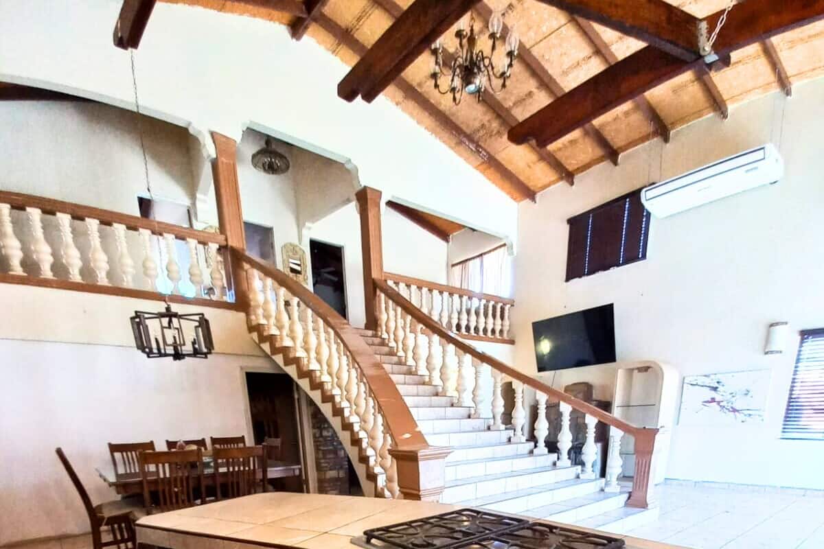 Une cuisine spacieuse dotée d’un grand îlot central, de meubles en bois et d’un escalier menant à l’étage supérieur.