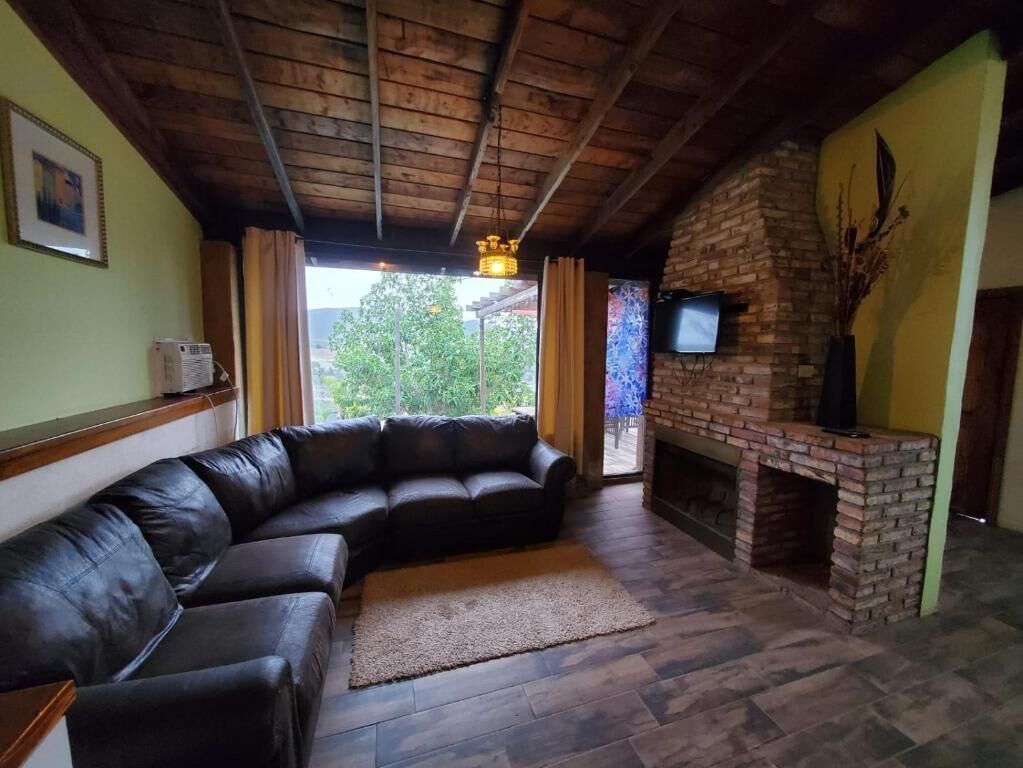 Una sala de estar con un sofá seccional de cuero, una chimenea de ladrillo y un televisor montado en la pared.