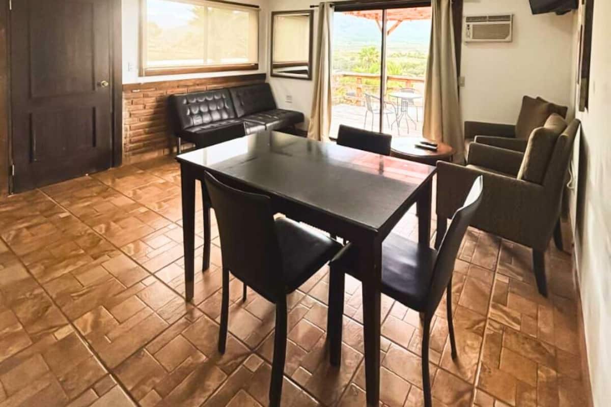 Un espace repas comprenant une table et des chaises, un banc et une vue à travers une porte vitrée.