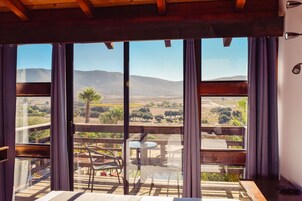 Un balcón con vistas a un paisaje montañoso, una mesa y sillas.