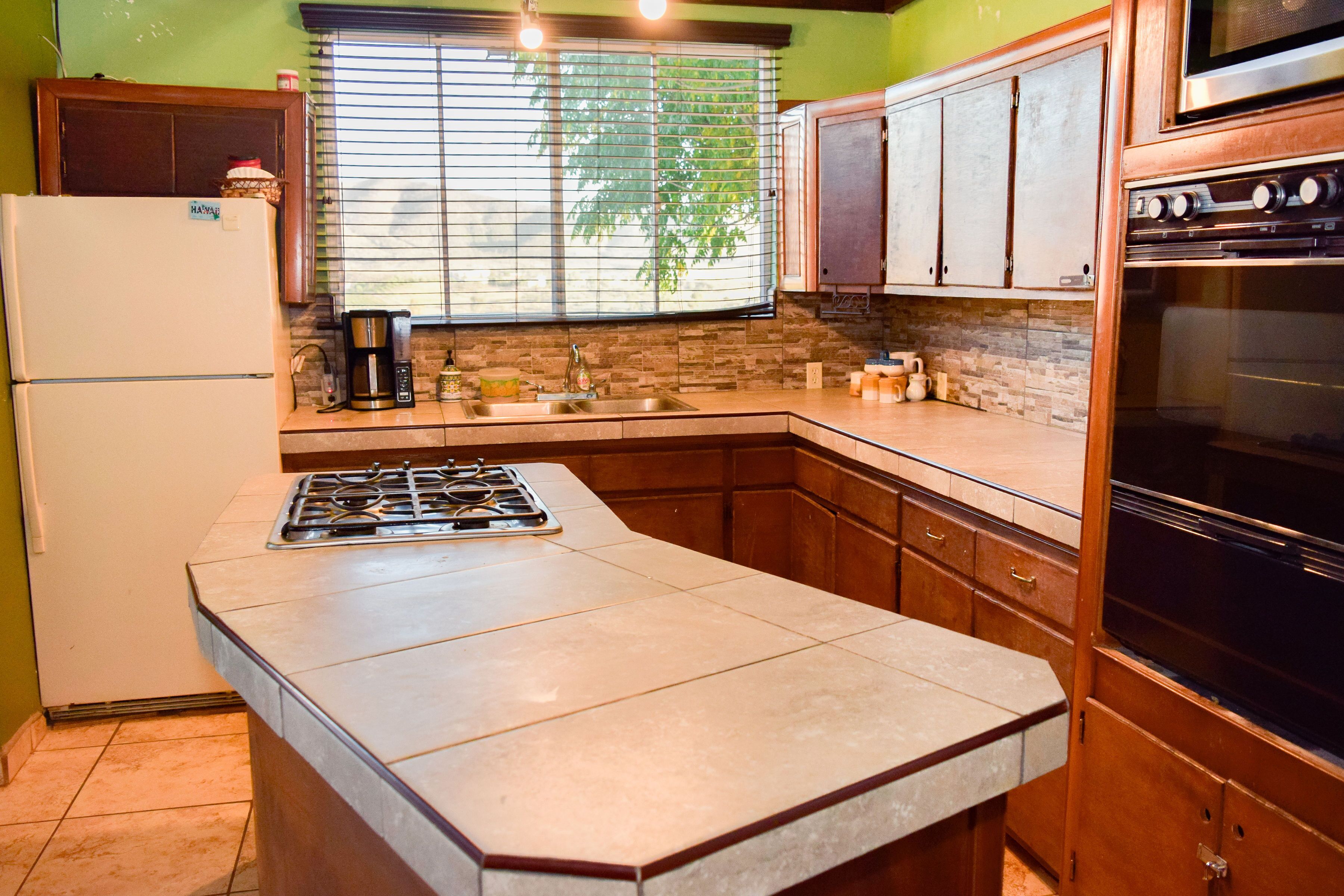 A kitchen with a central island, a stove, a sink, and wooden cabinets.