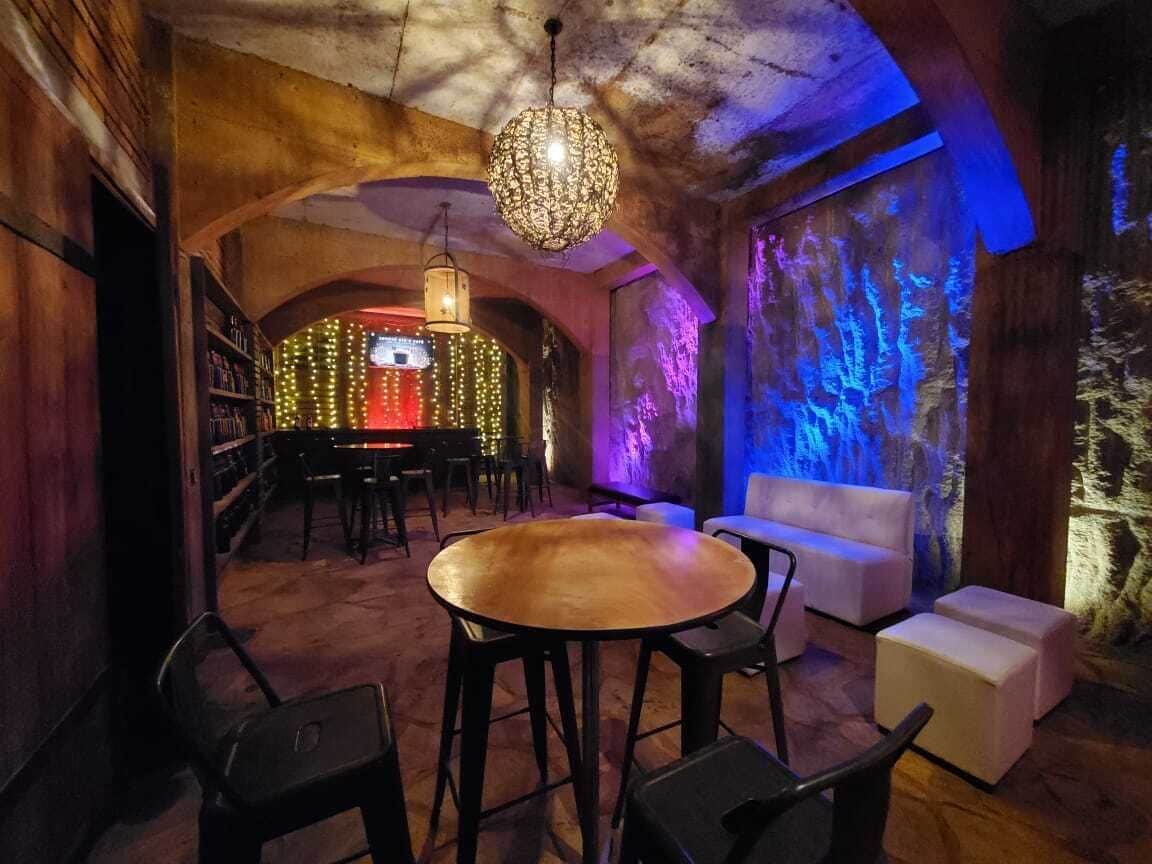An interior with a round wooden table, black chairs, a white sofa, and a hanging light fixture.