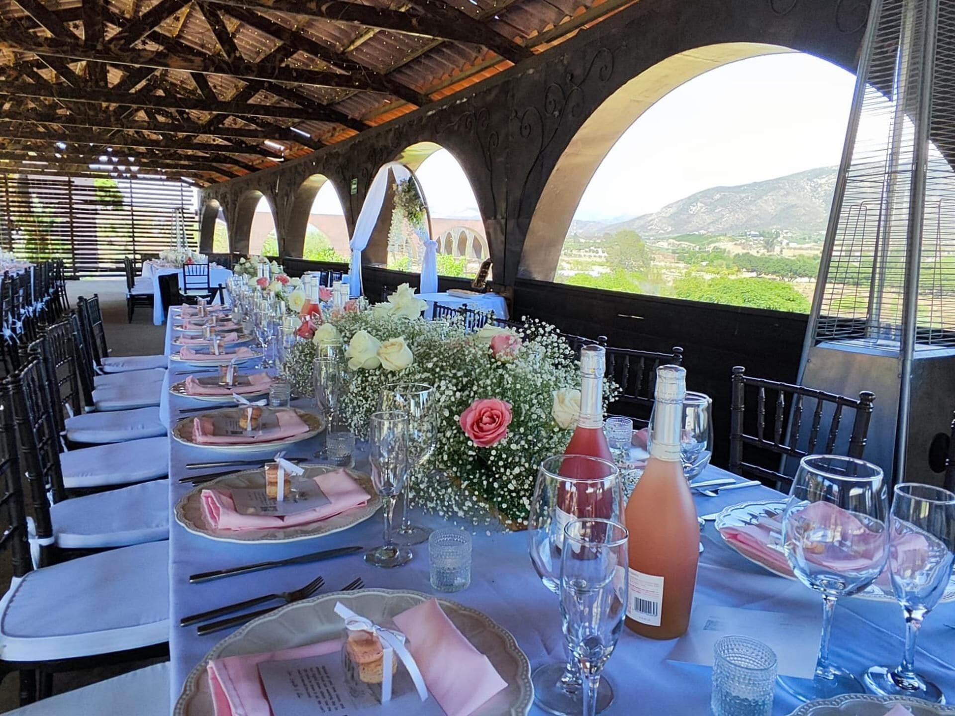 A long dining table set for a formal event with floral centerpieces, wine glasses, and neatly arranged place settings.