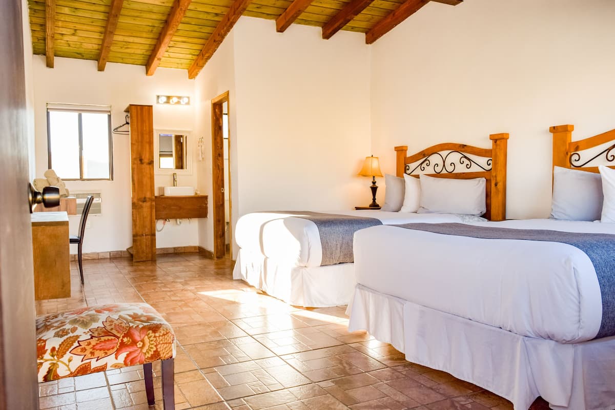 Une chambre avec deux lits, un plafond en bois, une salle de bain avec un miroir et une chaise.