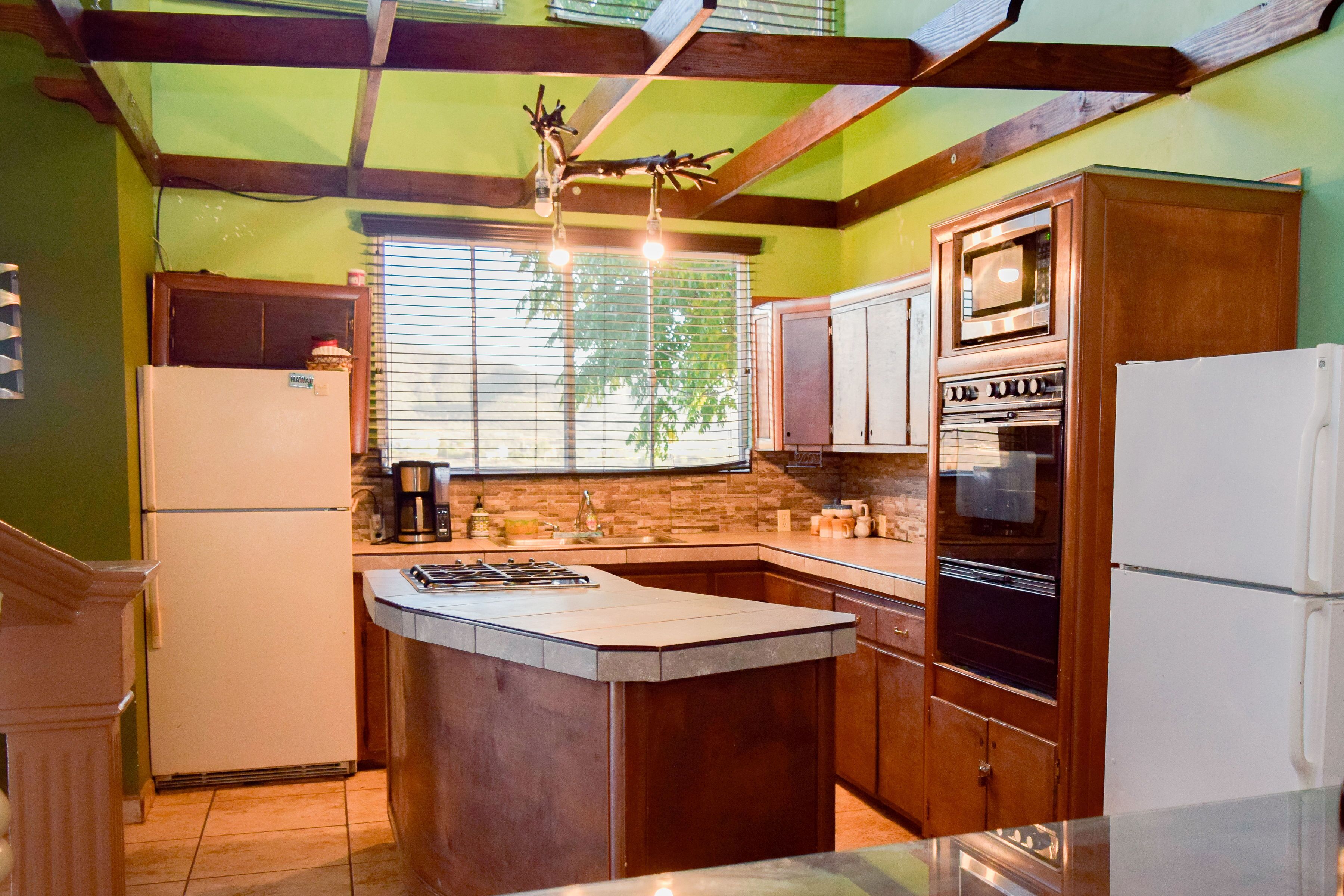 A kitchen with a central island, wooden cabinets, a built-in oven, and a refrigerator.