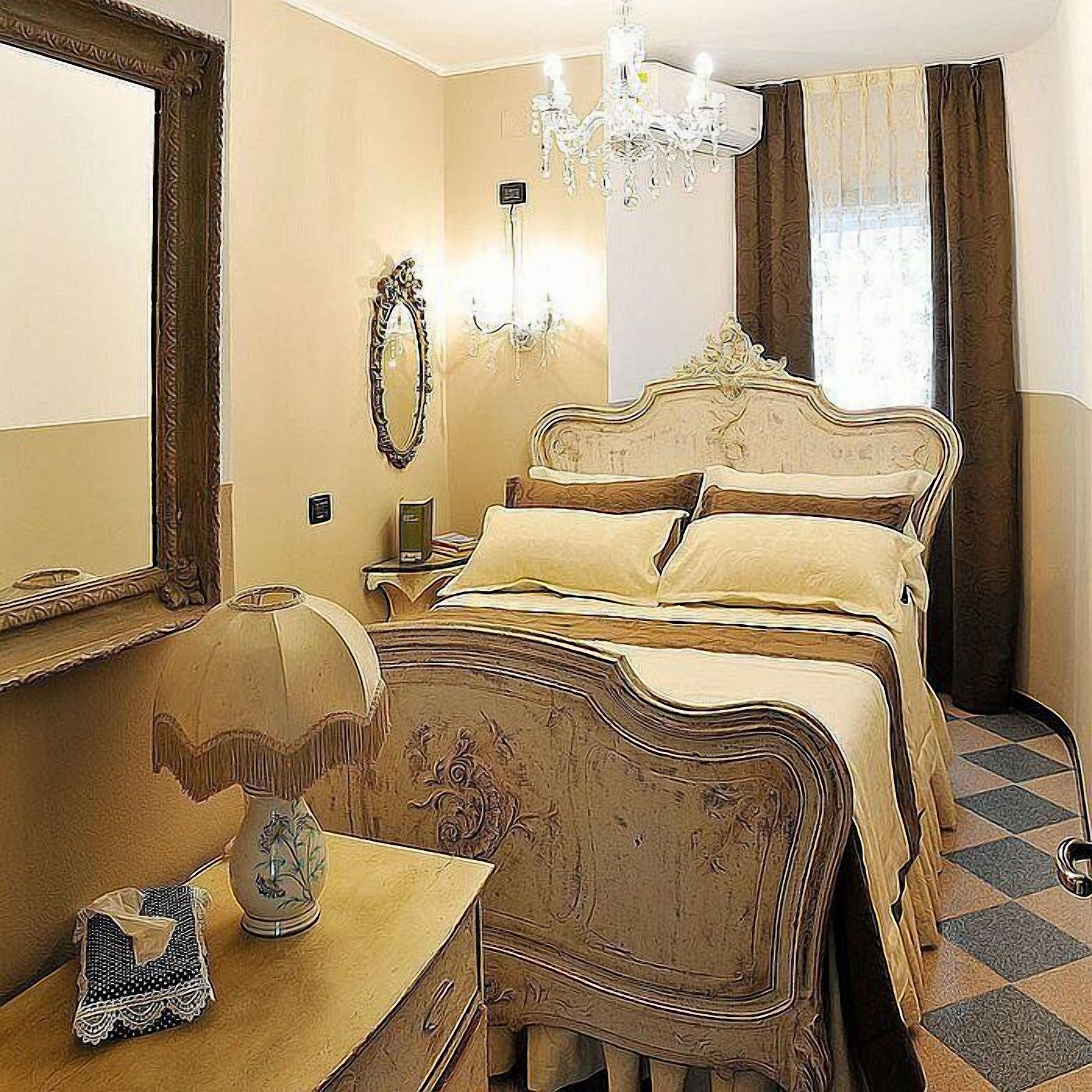 Una habitación de hotel con una cama grande, un candelabro, un espejo y un aparador.