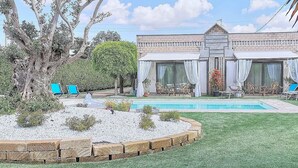 Ein Wohnhaus mit Pool, Sitzgelegenheiten im Freien und einem gepflegten Rasen.
