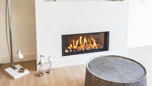 A modern living room with a flat-screen TV mounted above a fireplace, a floor lamp, and decorative bird sculptures.