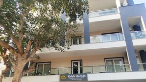 A multi-story building with a sign for Krish Homes, featuring a modern design with balconies and potted plants. - Pacific Inn Sec. 46 (Gurugram)